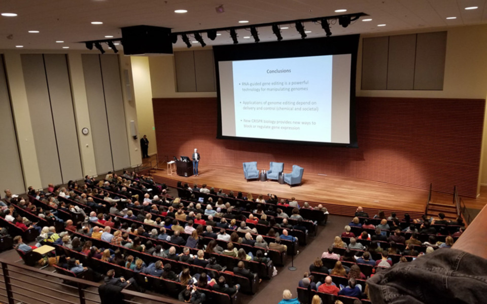 Image of Doudna giving a lecture to a large crowd