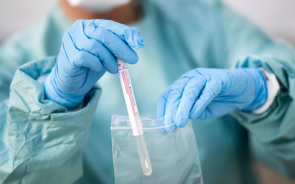 Science coronavirus testing header Image of scientist packing swab test into plastic bag
